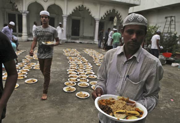 Muslims carry plates of food to attend an Iftar, or the meal that breaks the day`s fast, during the holy month of Ramadan at a mosque in Guwahati.