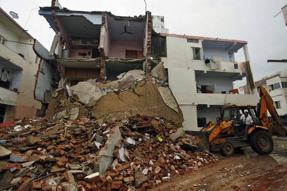 A man removes debris of a collapsed building in Ahmadabad. Three people were injured after part of a three-story building collapsed in Ahmedabad with many feared trapped in it, according to local reports.