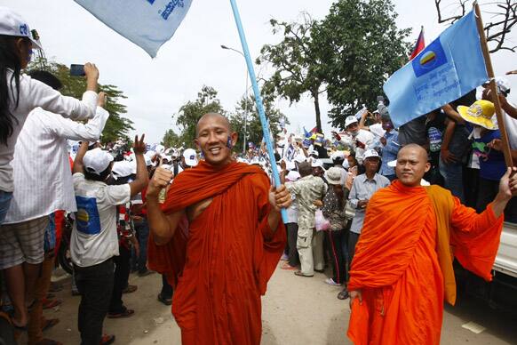 Buddhist monks carry the opposition Cambodia National Rescue Party flags during a final campaign rally in Phnom Penh, Cambodia.