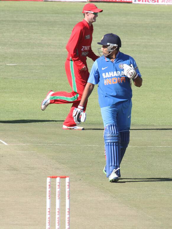 Indian batsman Rohit Sharma walks off the pitch after been dismissed for one run as Zimbabwean players celebrate his wicket on the second day of the one day international against India in Harare.