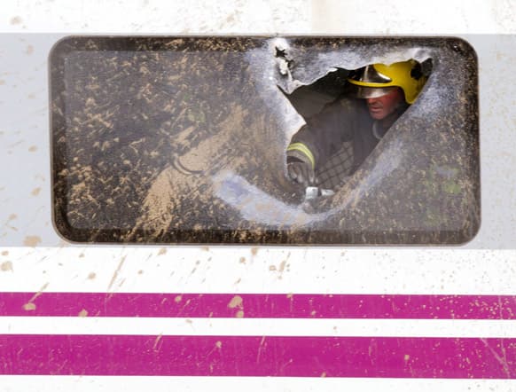 A firefighter works inside a derailed carriage at the site of a train accident in Santiago de Compostela, Spain