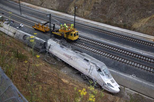 Rail workers are seen next to derailed cars at the site of a train accident in Santiago de Compostela, Spain.