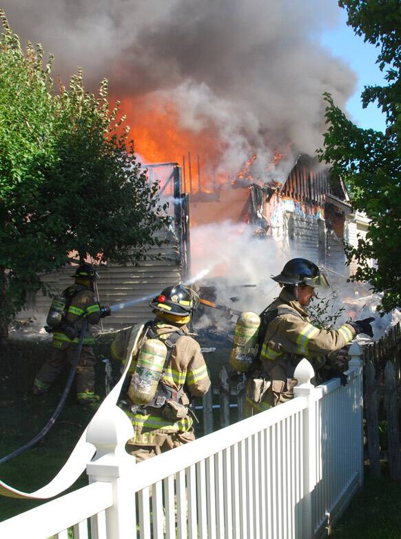 Firefighters stretch out a hose to begin fighting the ensuing fire after a small plane crashed into a home, in Columbus, Ind.
