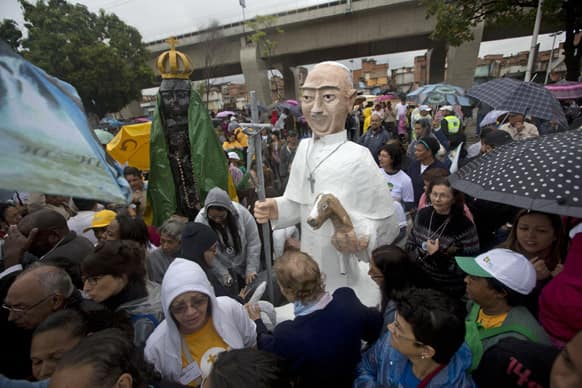 Large puppets that resemble Pope Francis, right, and the Virgin of Aparecida, Brazil`s patron saint, stand tall among residents waiting for Pope Francis` arrival to the Varginha slum Rio de Janeiro, Brazil.