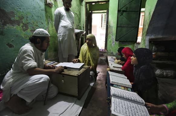 A young Indian Muslim girl takes lessons on the Quran from her teacher at a local Madrasa, or Muslim religious school, during Ramadan in New Delhi.
