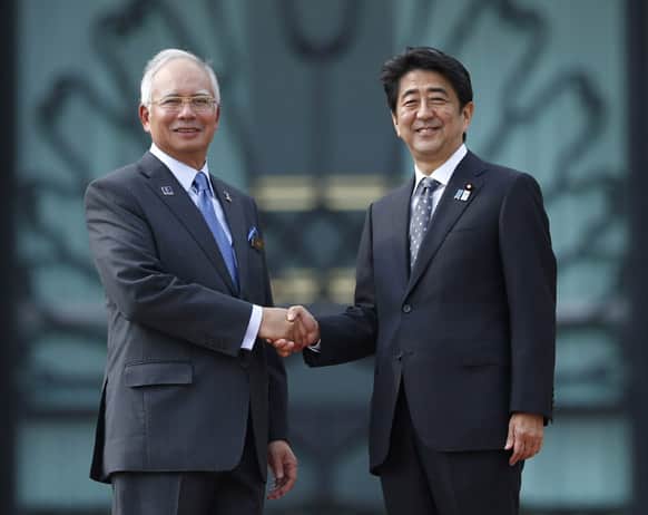 Japanese Prime Minister Shinzo Abe, right, poses with his Malaysian counterpart Najib Razak for photographers after a welcome ceremony in Putrajaya, Malaysia.