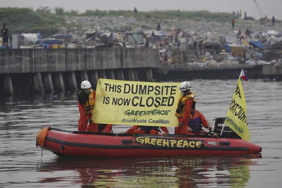 Environmentalists display a banner with slogan after placing ropes along a pier to prevent barges from transporting garbage outside a dumpsite in Manila, Philippines.