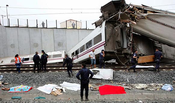 Emergency personnel respond to the scene of a train derailment in Santiago de Compostela, Spain. A train derailed in northwestern Spain on Wednesday night, toppling passenger cars on their sides and leaving at least one torn open as smoke rose into the air.