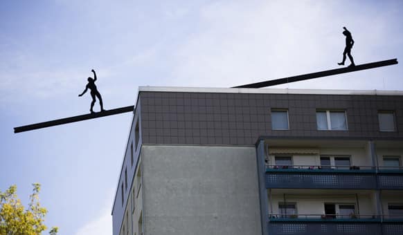 Two aluminum figures of an installation are silhouetted on a rooftop in Berlin, Germany. The installation of German artist Hubertus von der Goltz is called
