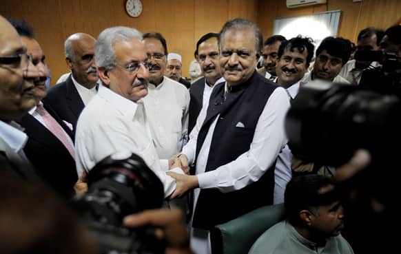 Mamnoon Hussain, center right, a candidate from ruling party Pakistan Muslim League-N shakes hands with Raza Rabbani, a candidate from opposition party Pakistan People Party after submitting their nomination papers for upcoming presidential election in Islamabad.
