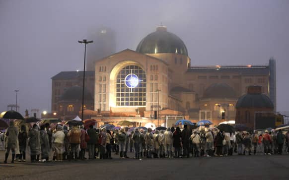 Pilgrims wait under the rain outside the Aparecida basilica for the arrival of Pope Francis in Aparecida, Brazil.