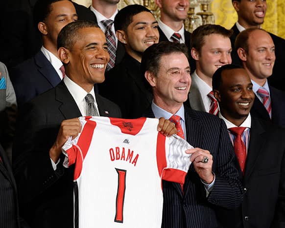 President Barack Obama and Louisville men`s basketball coach Rick Pitino, center, hold a Louisville basketball jersey as they pose for a photo with the 2013 NCAA Men’s Basketball Champions Louisville Cardinals, in the East Room of the White House in Washington.