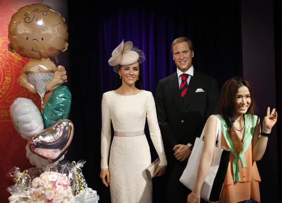 A visitor poses for a picture with wax figures of Britain`s Prince William and wife Kate as balloons are displayed in celebration of the birth of the couple`s first child, at Madame Tussauds in Tokyo.