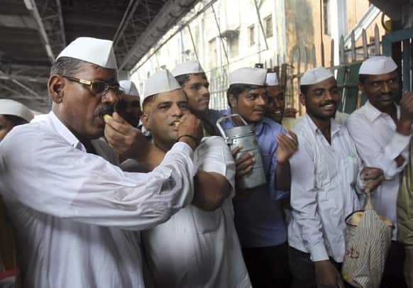 Dabbawalas, or lunchbox delivery men, pass out sweets in celebration of the birth of the Prince of Cambridge, the son of Britain`s Prince William and Kate, Duchess of Cambridge, at a railway platform in Mumbai.