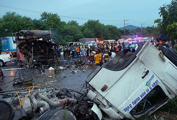 The charred wreckage of a double-decker passenger bus, top left, sits in the middle of a highway after a collision with a truck, foreground, in Saraburi province, northeast of Bangkok, Thailand. The bus caught fire after the collision early Tuesday, killing 19 people and injuring 20 others, authorities said.