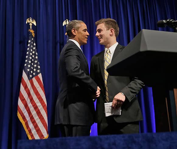 President Barack Obama, left, is introduced by Organizing for Action (OFA) field rep William Townsend, of Black Forest, Colo., before speaking at the event, in Washington.