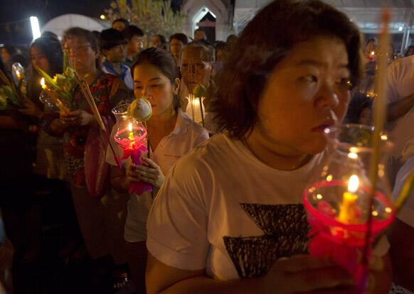 Thai Buddhist carrying lotuses and candles pray in front of Marble Temple during Asalha Bucha in Bangkok.