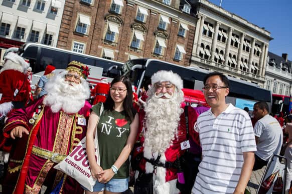 Santas pose with tourists after their parade during the World Santa Claus Congress at the famous pedestrian street Stroget in Copenhagen.