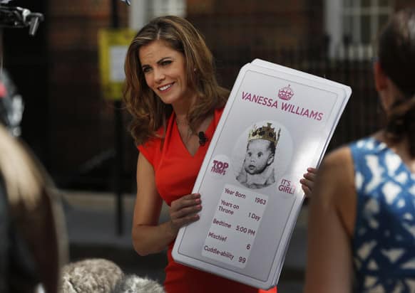 Broadcaster Natalie Morales of NBC holds placards made by a games company featuring a picture of guest co-host Vanessa Williams as a `royal baby` during a live broadcast across St. Mary`s Hospital exclusive Lindo Wing in London.