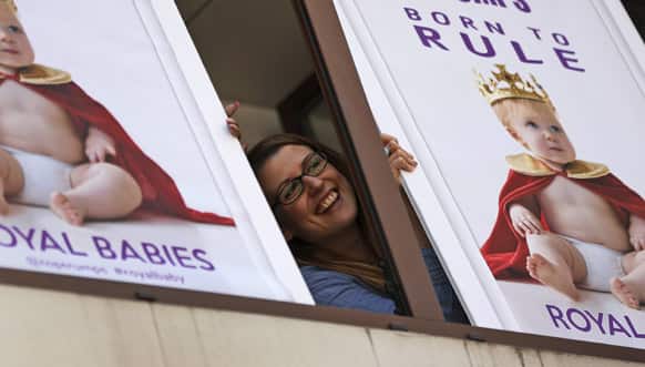 A worker of a games company laughs as she poses for members of the media with placards, depicting a `royal baby` near the St. Mary`s Hospital exclusive Lindo Wing in London.