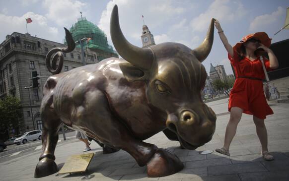 A visitor poses with Italian-American artist Arturo Di Modica`s Charging Bull statue in Shanghai, China.
