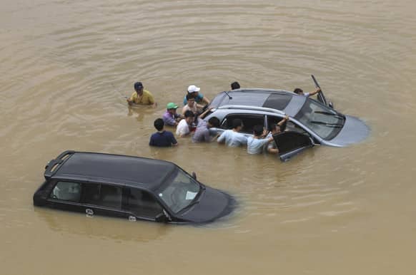 People push a vehicle submerged in a flood water after a torrential rain hit the metro area in Seoul, South Korea. Heavy rain battered the central part of the Korean Peninsula, including Seoul, Monday, flooding homes and roads, according to police.