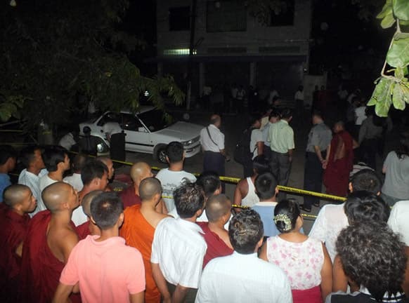 Buddhist monks and residents watch police examining a car after an explosion in Mandalay, central Myanmar. A small explosion went off Sunday near a firebrand monk as he was giving a sermon during a Buddhist ceremony, wounding five people, police and witnesses said Monday.