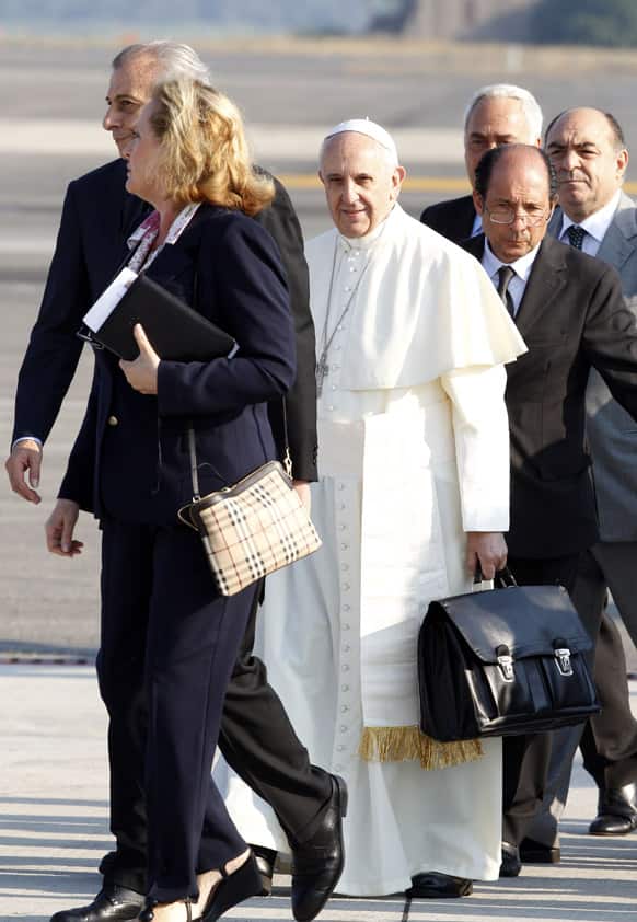 Pope Francis holds a bag at Rome`s Fiumicino international airport. It`s wheels up on Pope Francis` first trip abroad as pontiff.