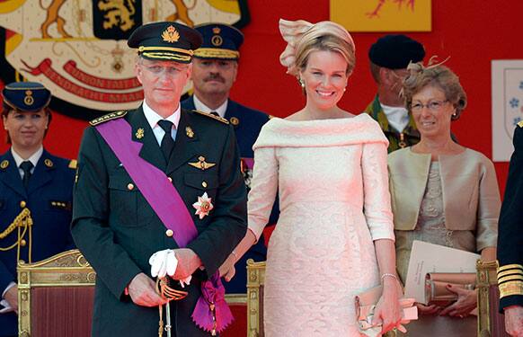 Belgium`s King Philippe, second left and Queen Mathilde, second right, review the troops during a military parade in Brussels.