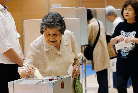 An elderly woman casts her vote in Japan`s upper house parliamentary elections at a polling station in Tokyo.