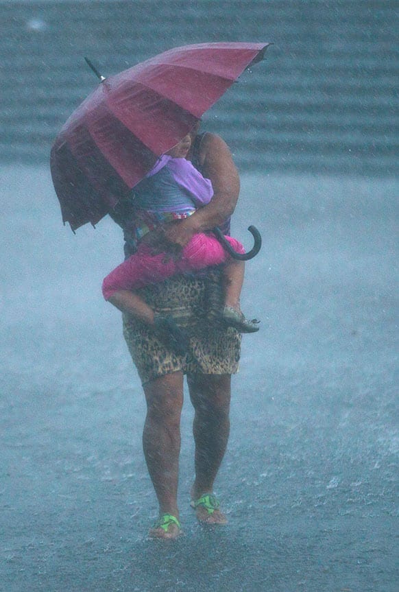 A woman carries a girl under an umbrella as it rains hard outside the Metropolitan Cathedral during a celebration honoring the