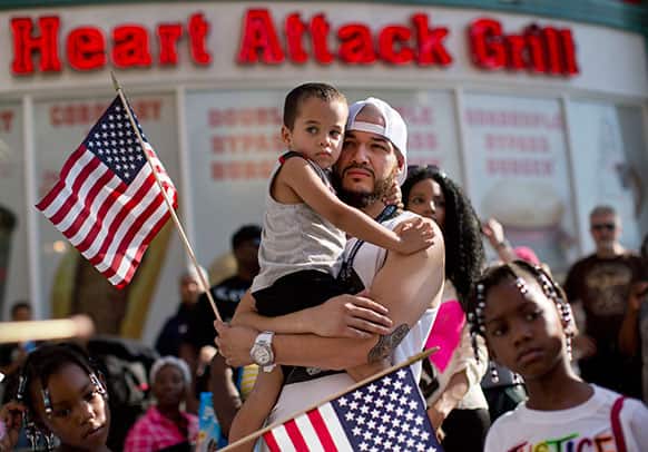 Ulysses Diaz, holds his son, Armani Hinton, as he listens to comments before marching in a rally, in Las Vegas.