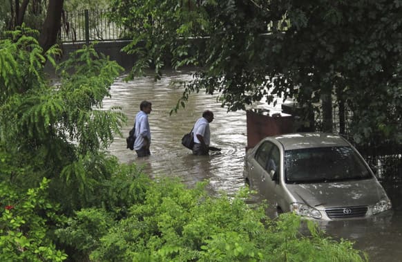 Men wade through a flooded street after heavy rainfall in New Delhi. Heavy rainfall lashed the national capital Saturday, flooding streets and homes and choking the city with traffic jams.