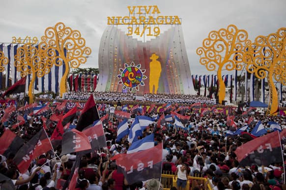 Backdropped by a screen that features a silhouette of Augusto Cesar Sandino, a sea of Nicaraguans cheer and wave Sandinista National Liberation Front, FSLN, banners and representations of their national flag during a rally marking the 34th anniversary of the Sandinista revolution in Managua.