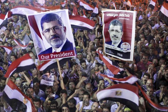 Supporters of Egypt`s ousted President Mohammed Morsi hold his posters and wave national flags as they protest in a park in front of Cairo University, where protesters have installed their camp in Giza, southwest of Cairo.