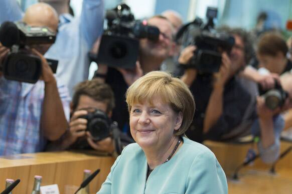 German Chancellor Angela Merkel is surrounded by photographers and television crews at the beginning of a press conference in Berlin, Germany.