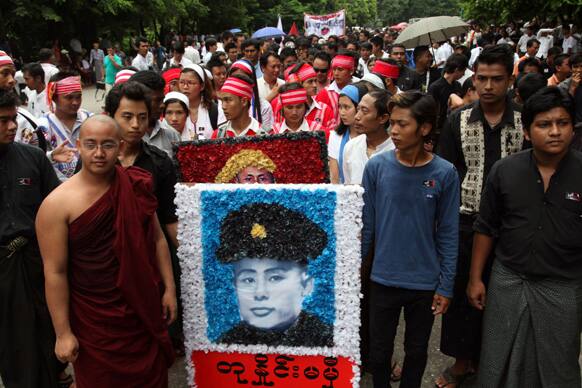 A Buddhist monk and people carry a portrait of Gen. Aung San as they line up to enter the Martyrs Mausoleum to salute Myanmar Independence Heroes during the country`s 66th anniversary Martyrs Day in Yangon, Myanmar.