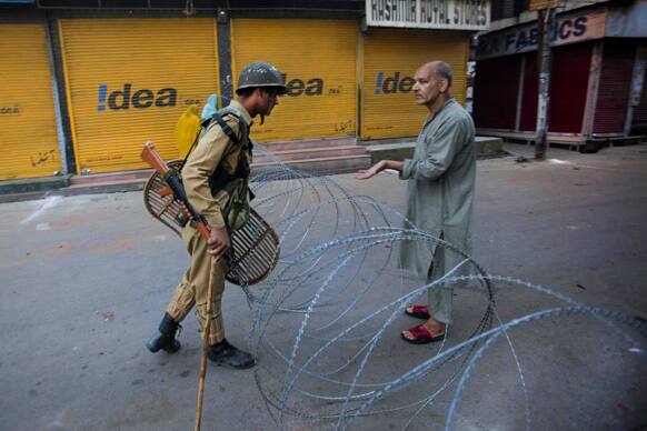 A Kashmiri man shows to an Indian paramilitary soldier signature of an officer signed on his palm for allowing him to pass through a temporary check point during curfew in Srinagar.
