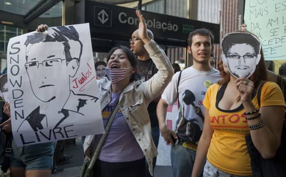 A demonstrator holding a poster with a drawing depicting National Security Agency leaker Edward Snowden shouts during a protest outside the regional office of the presidency in Sao Paulo, Brazil.