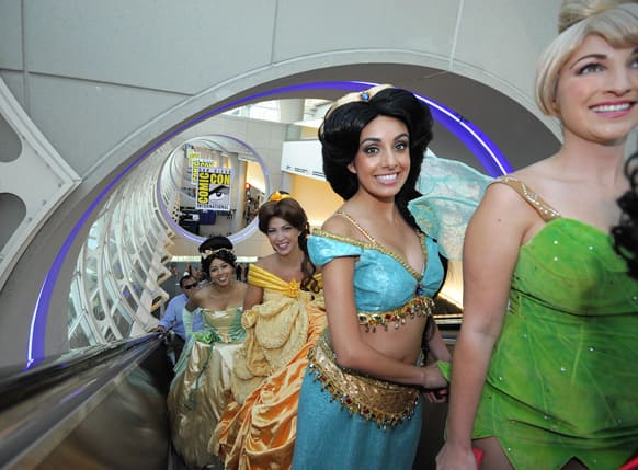 Fans dressed as Disney princesses ride the escalator as they get their credentials during the Preview Night event on Day 1 of the 2013 Comic-Con International Convention in San Diego, Calif.