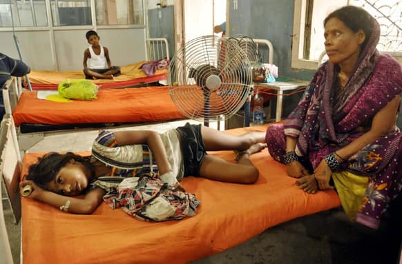 A woman sits beside a child who fell sick after eating a free school lunch, at a hospital in Patna.