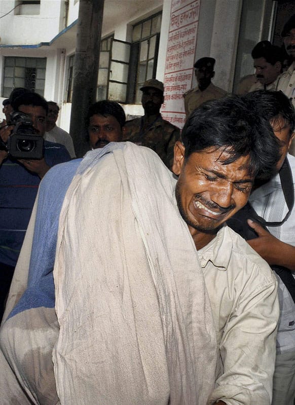 An Indian man cries while carrying the body of his daughter who died after eating a free school lunch at a hospital in Patna.