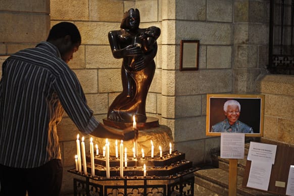 A man places a candle after he prayed for former South African president Nelson Mandela inside the St. George’s Cathedral in Cape Town, South Africa.