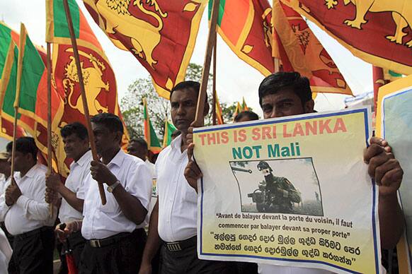 Sri Lankan pro-government supporters carry Sri Lankan national flags and a placard denouncing French forces in Mali during a protest outside the French Embassy in Colombo, Sri Lanka.