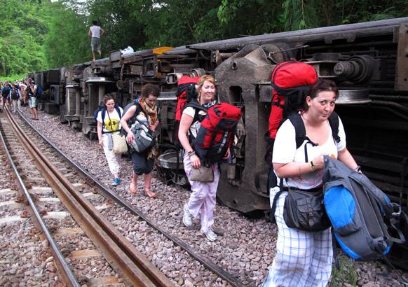 Passengers carry their belonging as they leave form a derailed train in Phrae province, northern Thailand. The passenger train derailed on old tracks in the mountains of northern Thailand early Wednesday, slightly injuring at least 30 passengers, mostly foreign tourists.