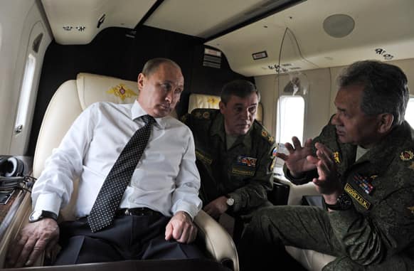 Russian President Vladimir Putin listens to Defense Minister Sergei Shoigu as he observes military exercises from a helicopter near the Baikal Lake.
