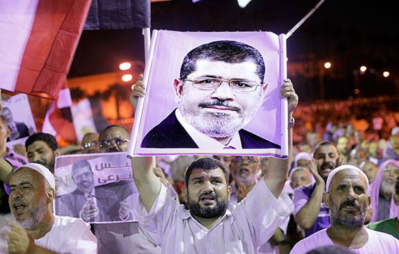 Supporters of Egypt`s ousted President Mohammed Morsi chant supporting slogans they hold his poster during a rally in a park in front of Cairo University, where protesters have installed their camp in Giza, southwest of Cairo, Egypt.