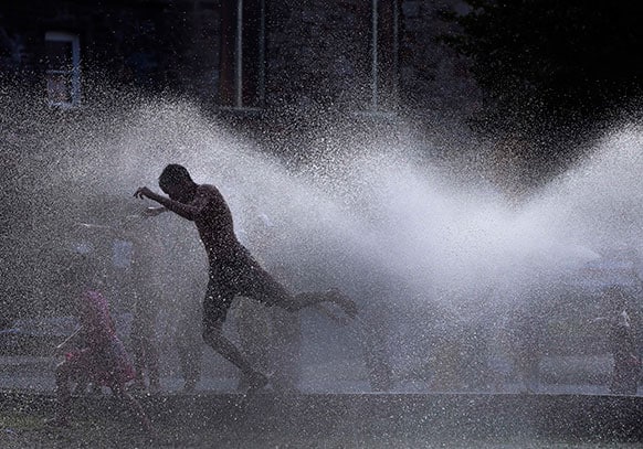 Kids cool off in the spray of an open hydrant on a hot evening in Lawrence, Mass. Area temperatures during the day reached into the 90s.