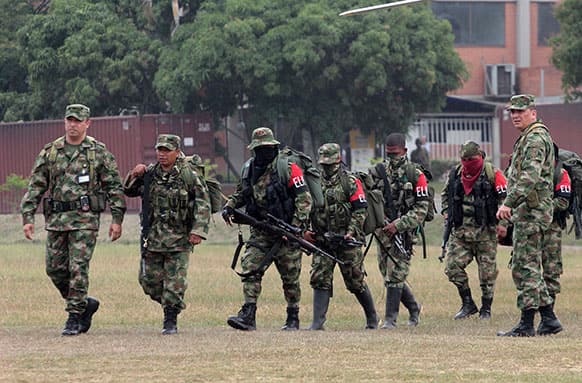 Soldiers, left and right, escort rebels of the National Liberation Army, ELN, who gave themselves up upon their arrival to a military base in Cali, Colombia.