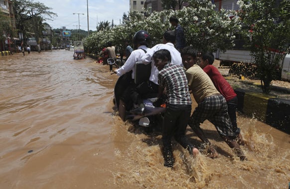 Children push a scooter through a waterlogged street in Guwahati. Heavy showers flooded some areas in the city.